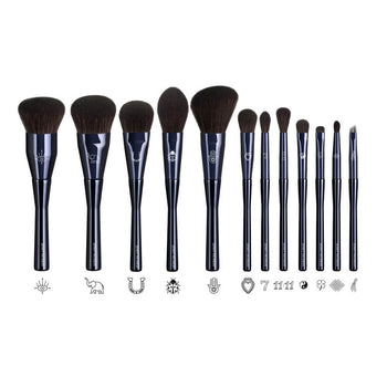Twelve deep navy makeup brushes from The Superstition Set showing laser-engraved good-luck symbols on each ferrule